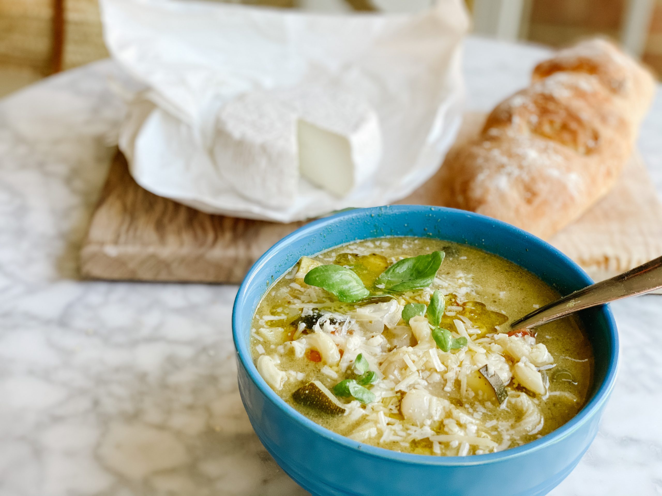 Soupe au Pistou in a blue bowl with baguette and goat cheese
