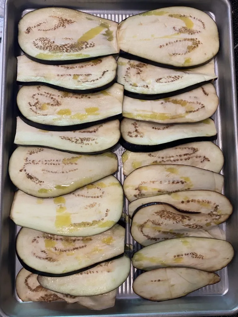 large eggplant slices on a metal cooking sheet, drizzled with olive oil