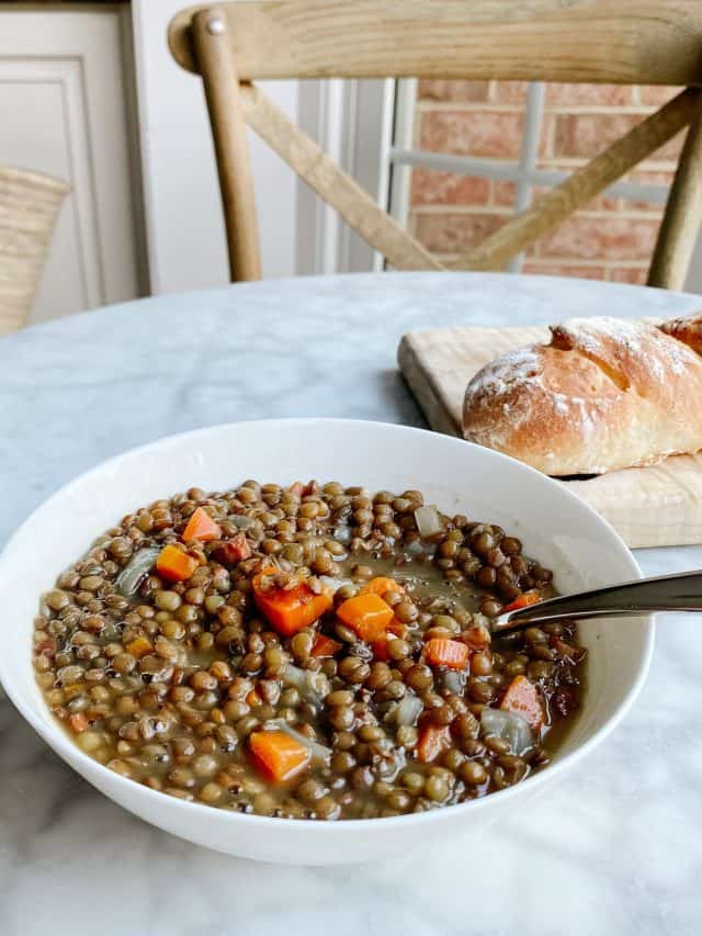 French Lentil Soup made with lentils, carrots and pancetta in a bowl with baguette