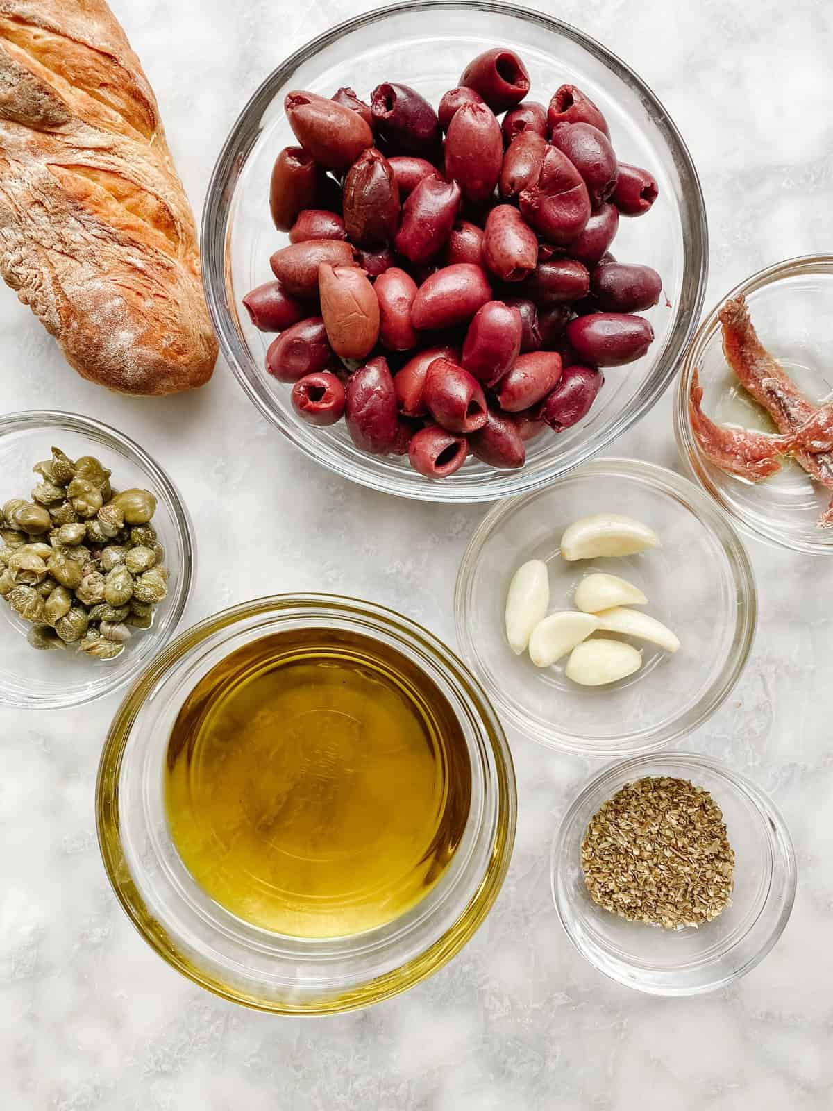 glass bowls with French Riviera ingredients. Olive oil, olives, garlic, herbes de provence, capers