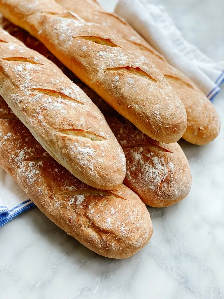 5 French baguettes on a marble table with a cloth