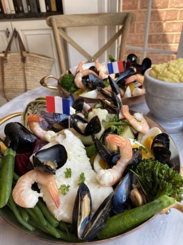 2 copper plates with Le Grand Aรฏoli, shrimp, cod, fresh vegetables, mussels a french baguette and aรฏoli