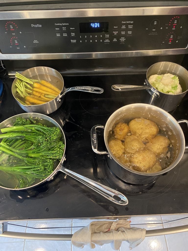 4 pots on a stove with vegetables