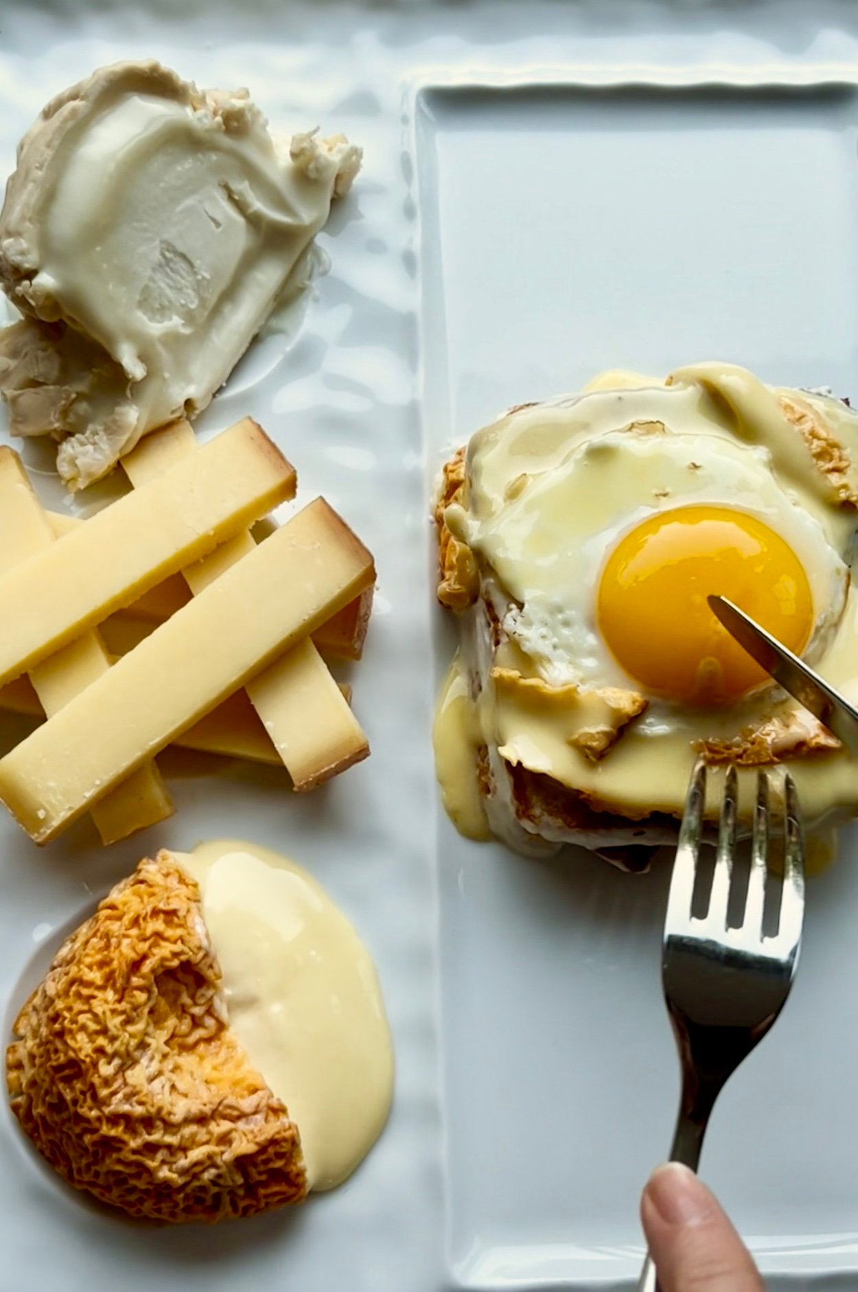 three cheese croque madame with knife and fork and three cheese on a plate