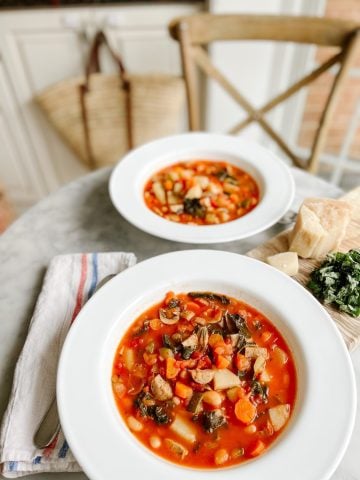 two bowls of Italian sausage and White bean soup with kale on a table