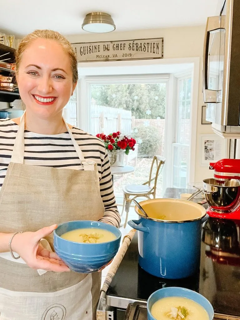 Le chef's wife holding a bowl of Magical Leek soup in her kitchen