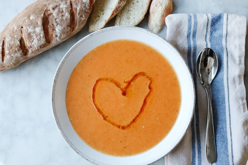 La Soupe de Mamie vegetable soup with an olive oil heart drizzled on top and a fresh baked baguette