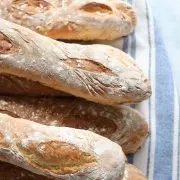 homemade French baguettes piled up on a striped cotton towl