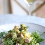 Parisian Potato salad on a plate with mixed greens and a glass of white wine