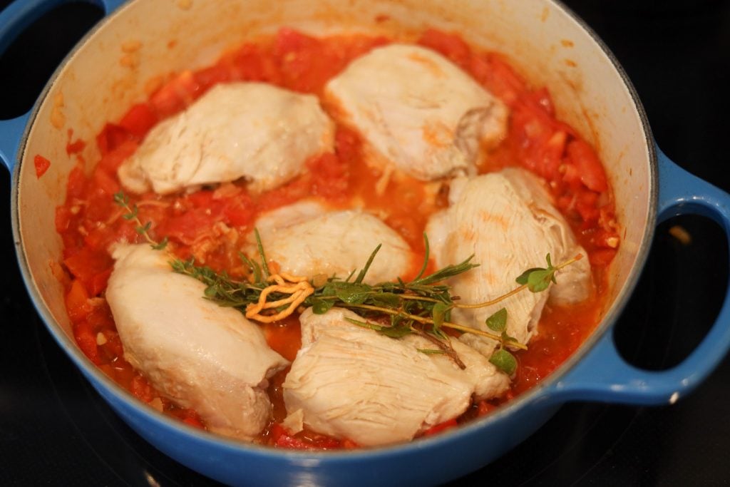 simmering the chicken thighs in the tomato pepper sauce