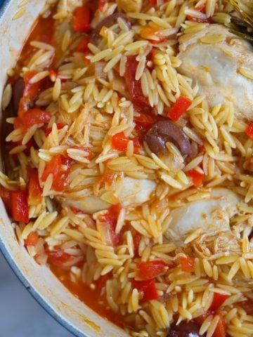 a pot of chicken, orzo and olives with herbes and peppers