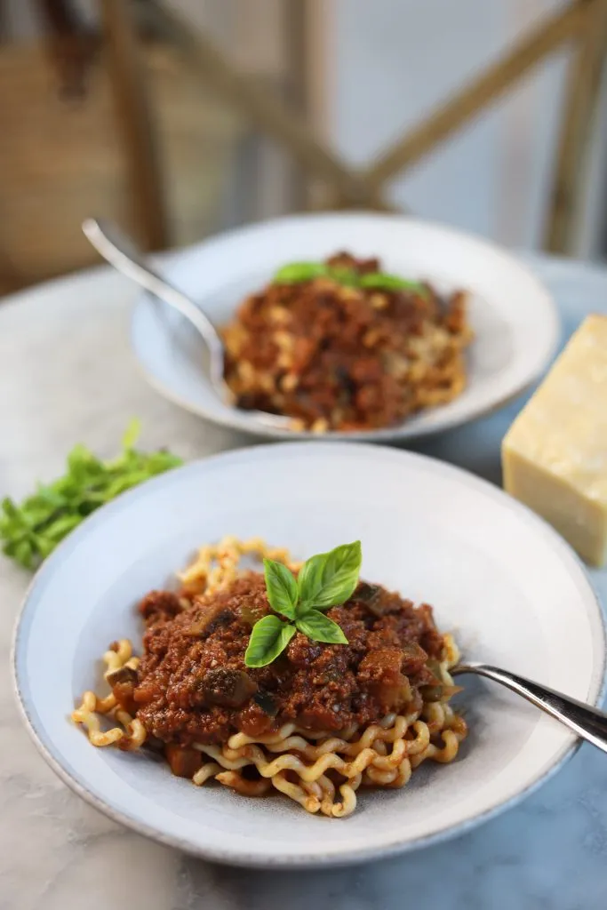 two bowls of eggplant ragu with basil over pasta