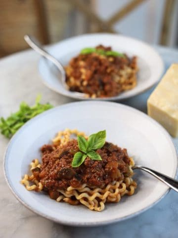 two bowls of eggplant ragu with basil over pasta