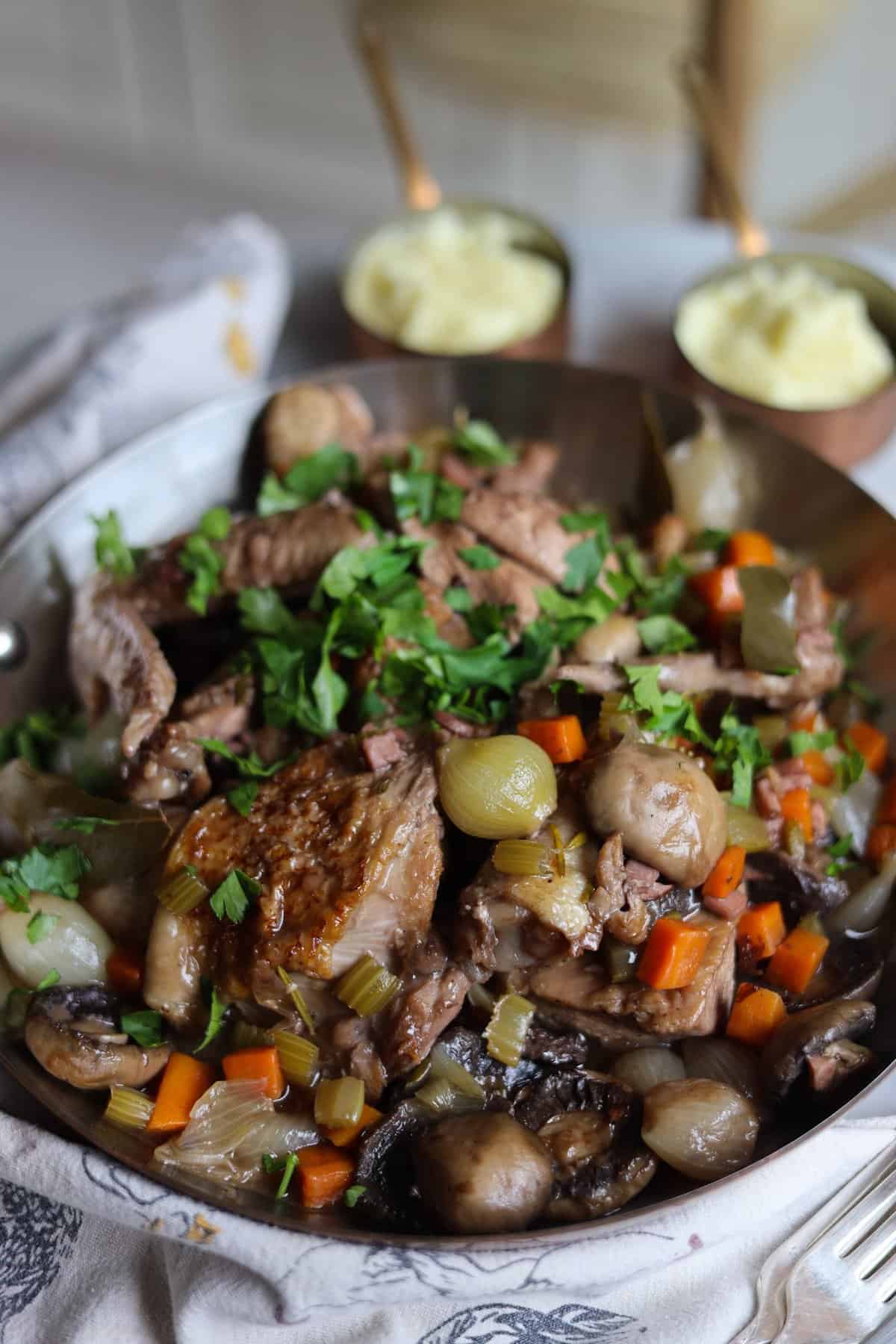 Coq au Vin with mushrooms, chicken, onions and parsley served with mashed potatoes