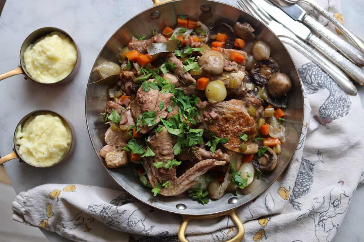 Coq au Vin with mushrooms, chicken, onions and parsley served with mashed potatoes