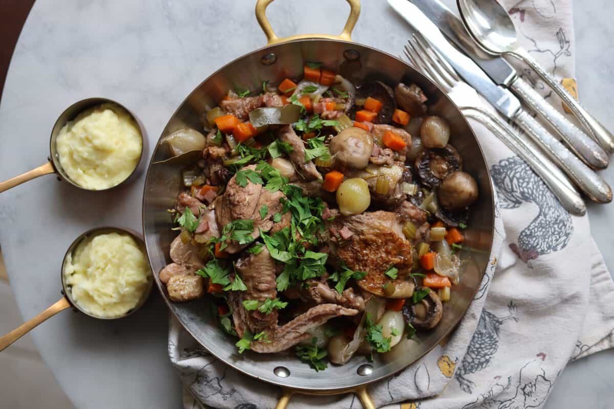 Coq au Vin with mushrooms, chicken, onions and parsley served with mashed potatoes