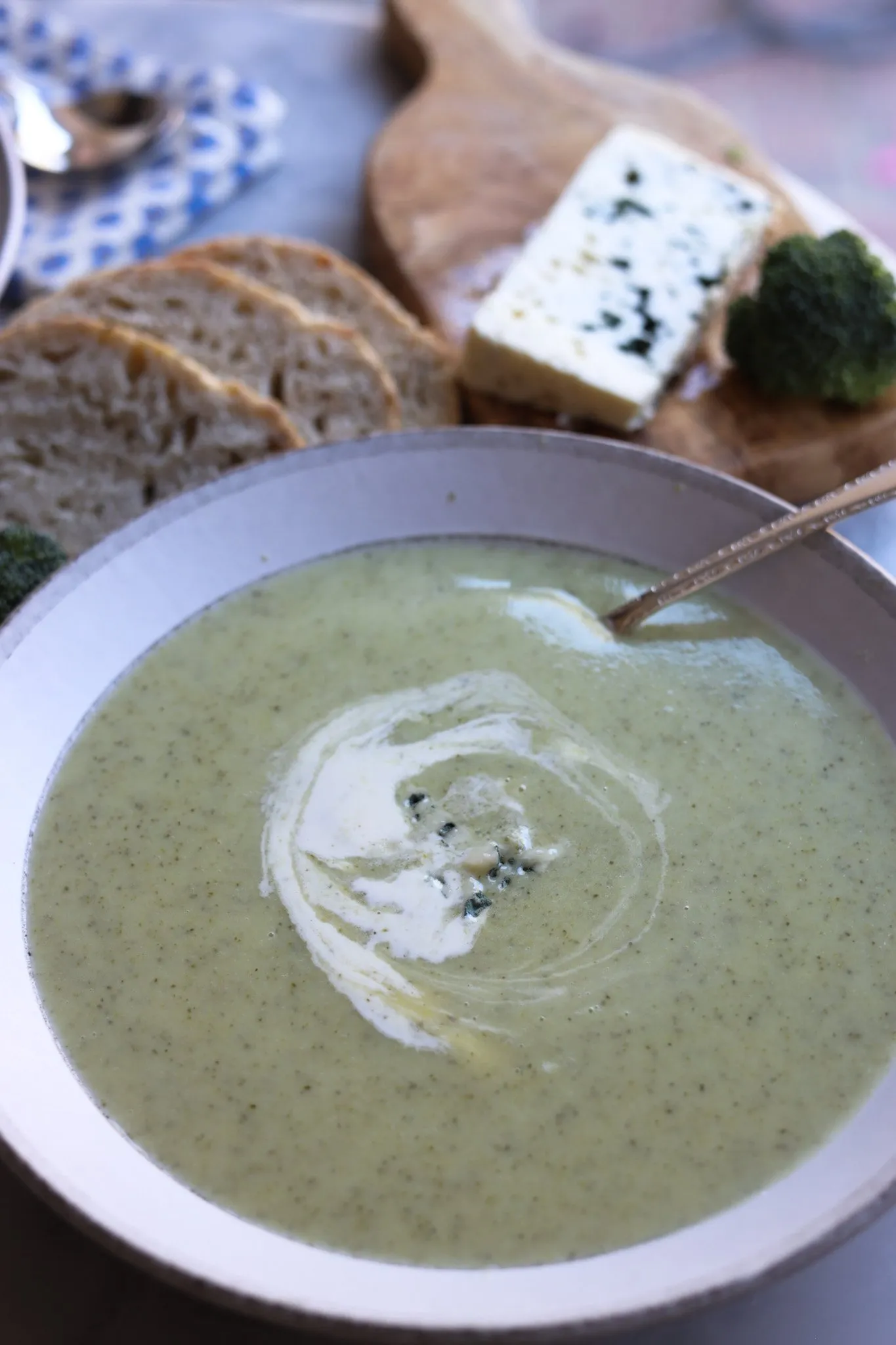 broccoli and blue cheese soup on a table with blue cheese and bread