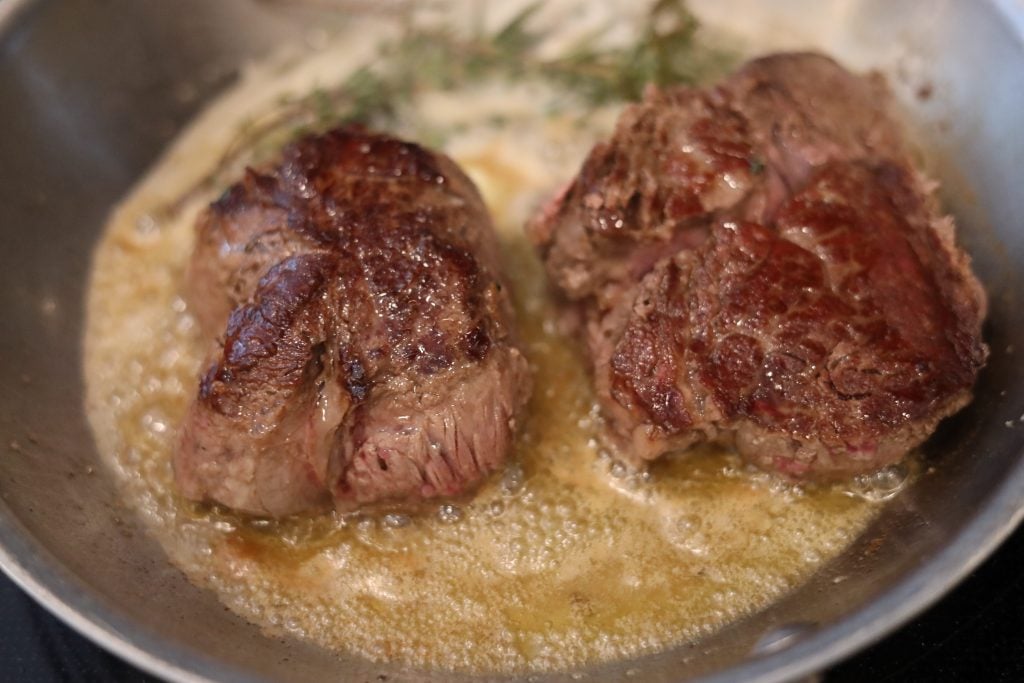 butter poached sirloin steaks in a pan