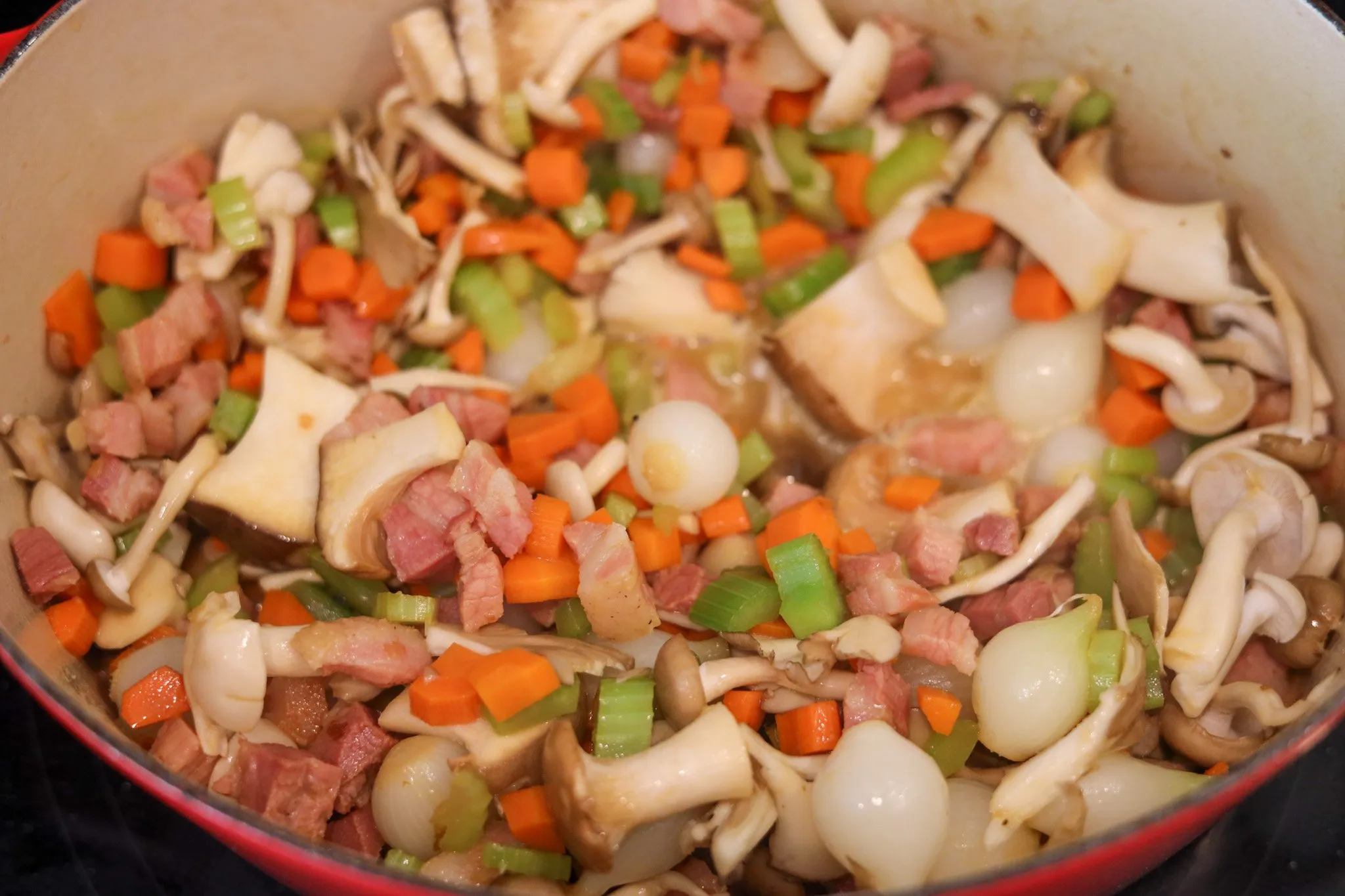 Sauteed Ingredients for coq au vin blanc - chicken, white wine, pork belly, celery, onions, mushrooms, parsley