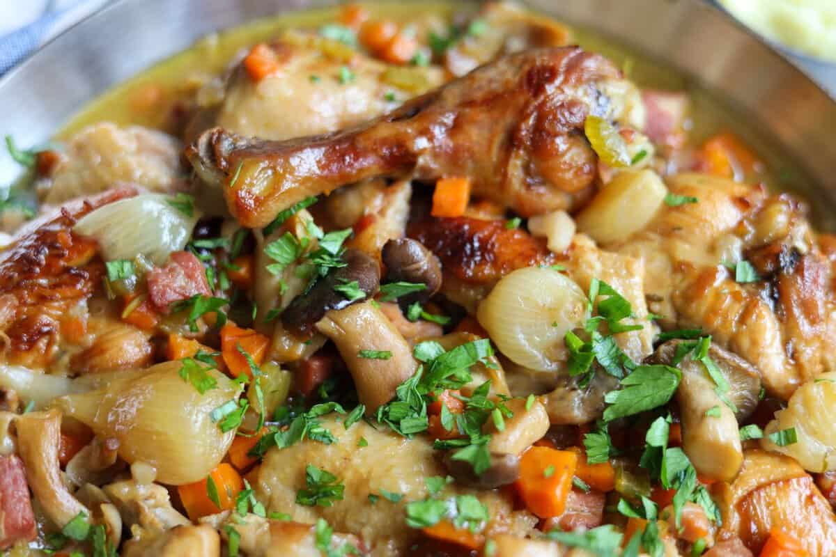 coq au vin blanc , a chicken stew with white wine, pork belly, celery, onions, mushrooms, parsley