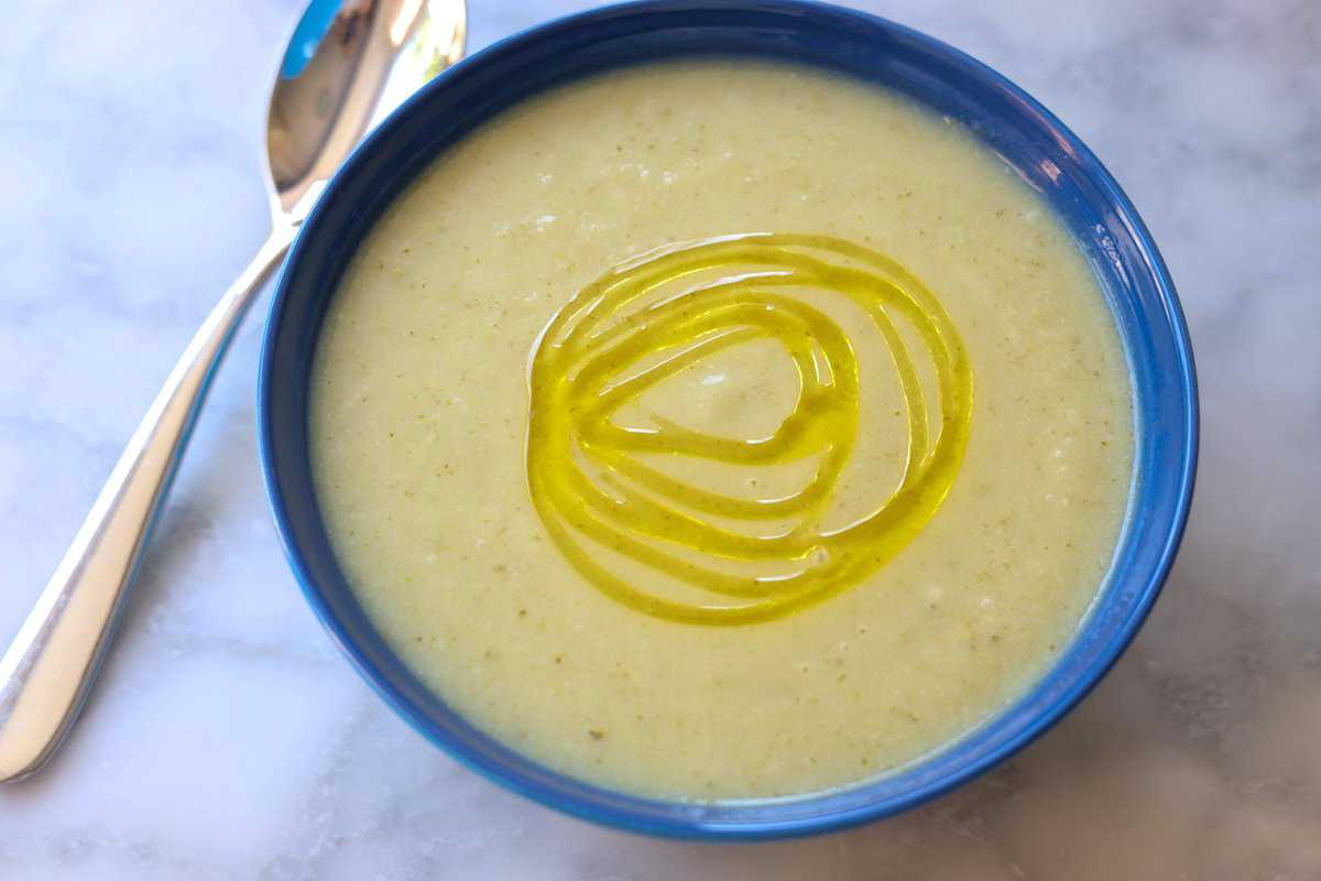 healthy broccoli and cauliflower soup in a bowl with a drizzle of olive oil on it