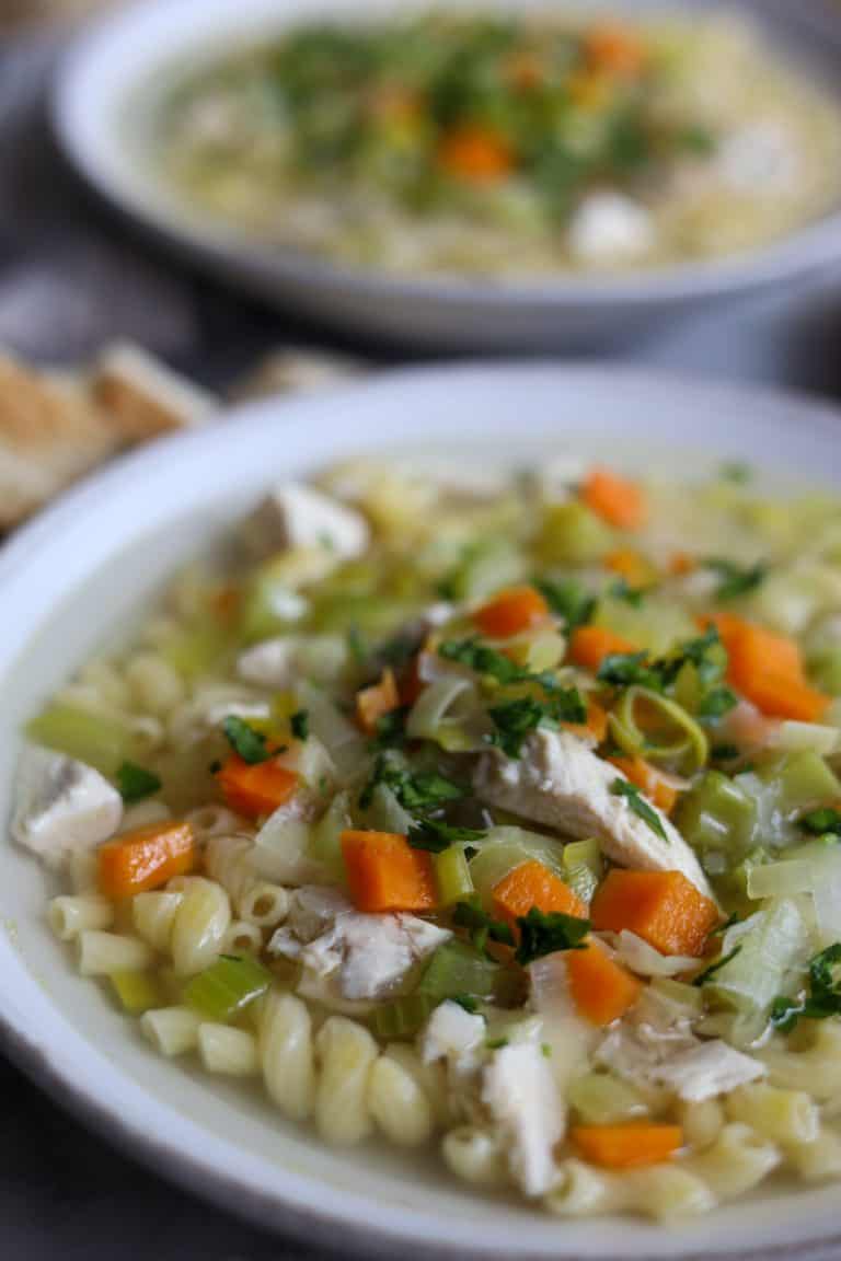 homemade chicken macaroni noodle soup with parmesan and parsley in a bowl