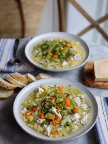 homemade chicken macaroni noodle soup with parmesan and parsley in a bowl