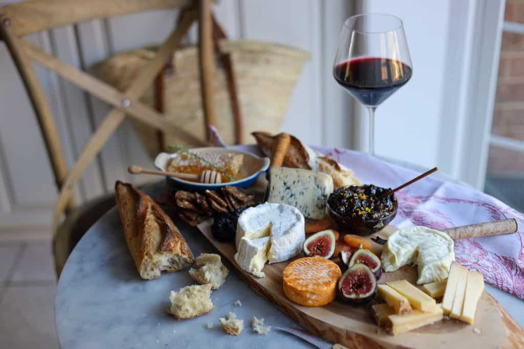 French cheese board with a glass of redwine and torn up baguette