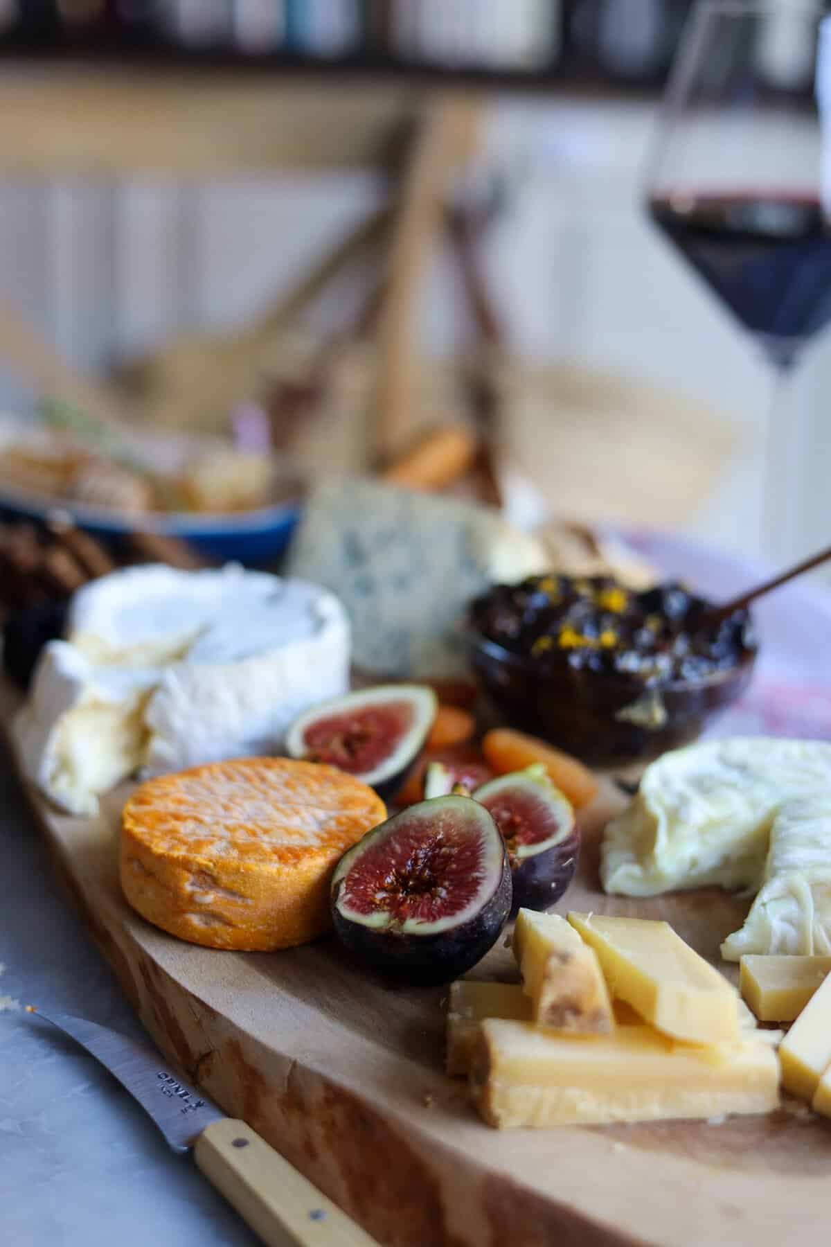 French cheese board - figs and french cheeses on a wood board with a glass of wine
