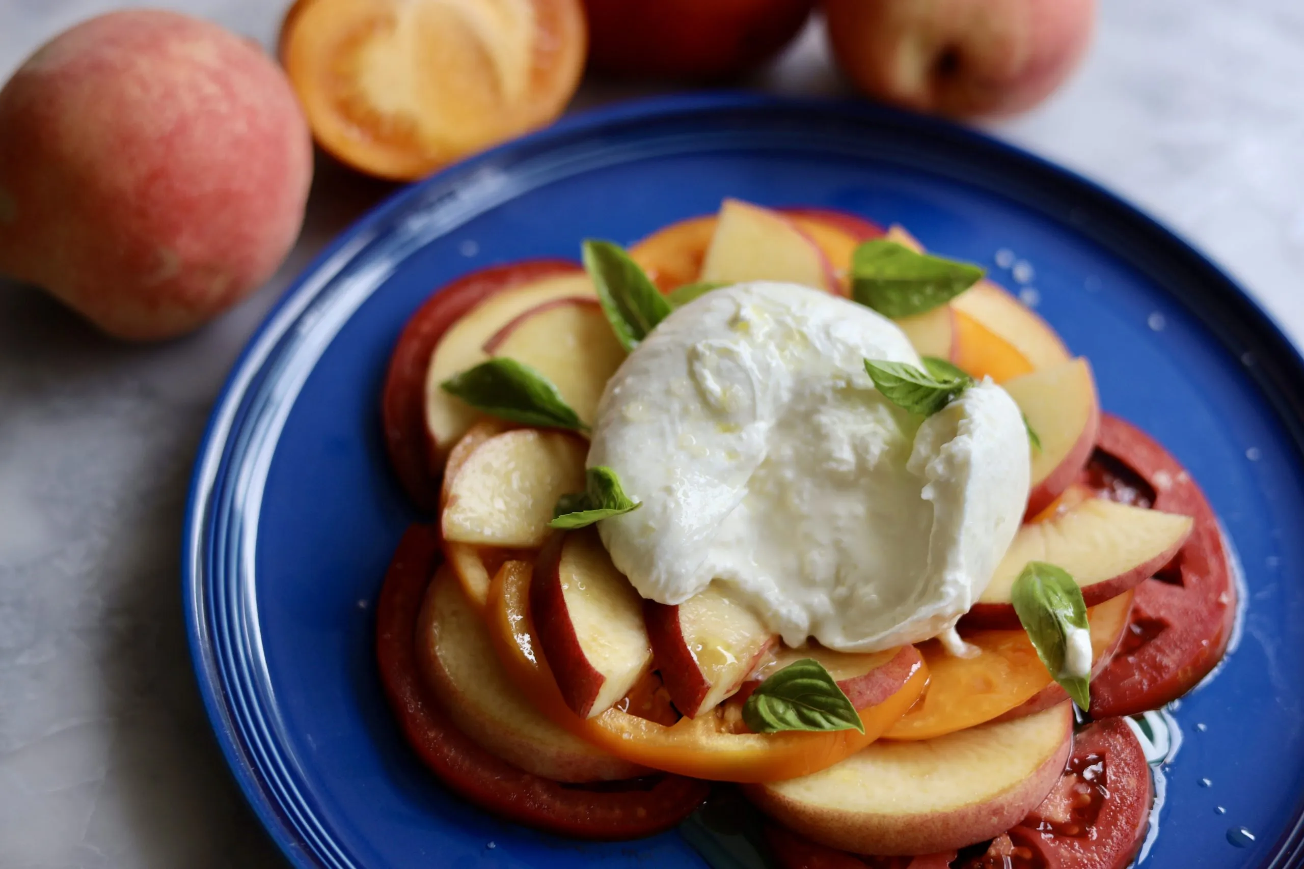 Peach caprese salad with peaches, tomatoes, burrata and basil