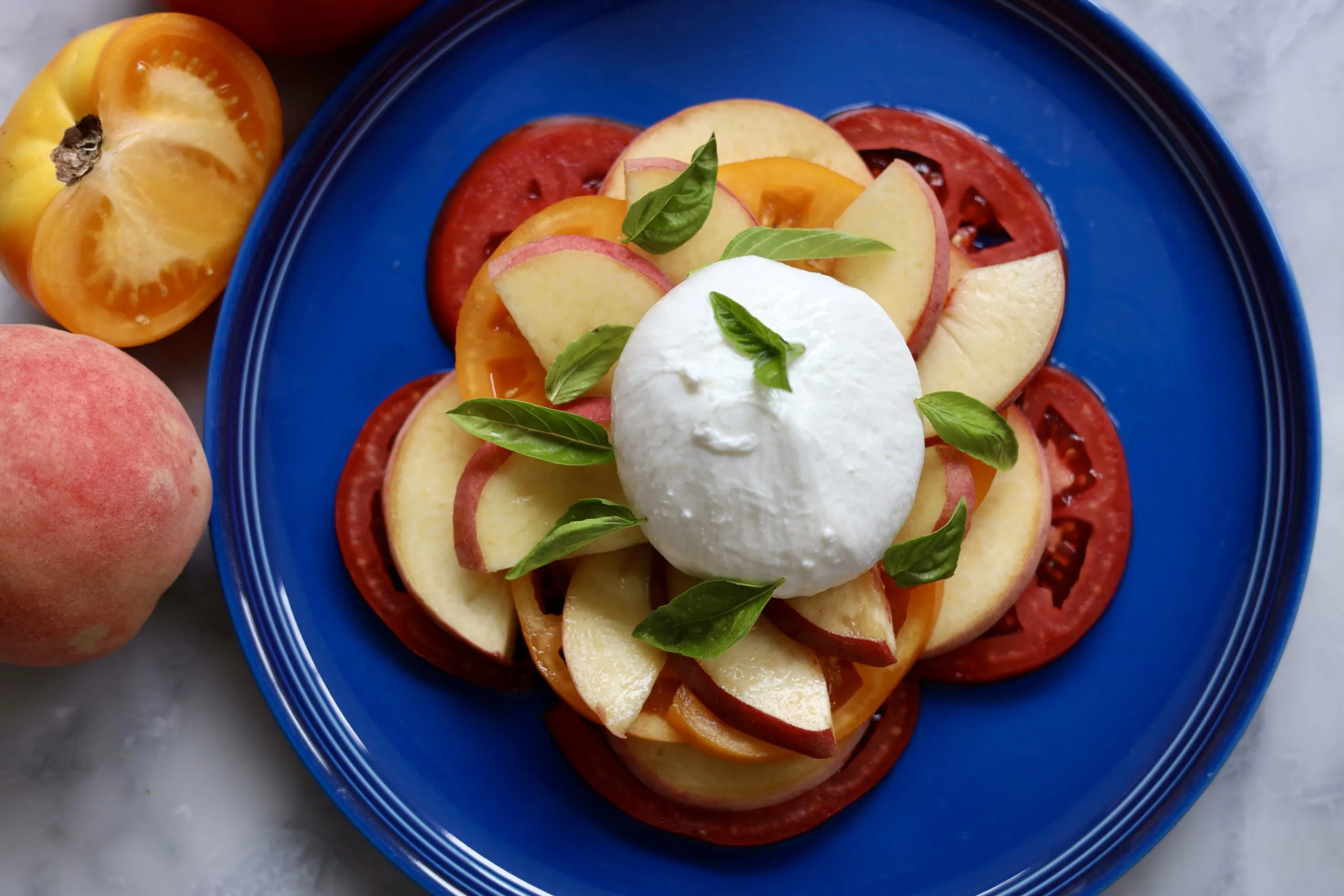 Peach caprese salad with peaches, tomatoes, burrata and basil