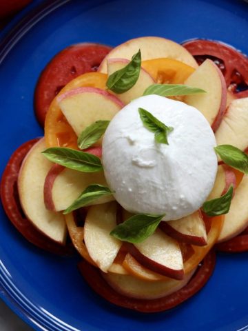 Peach caprese salad with peaches, tomatoes, burrata and basil