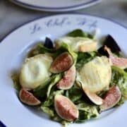 French warm goat cheese salad on a plate with figs and honey over warm goat cheese toasts and salad