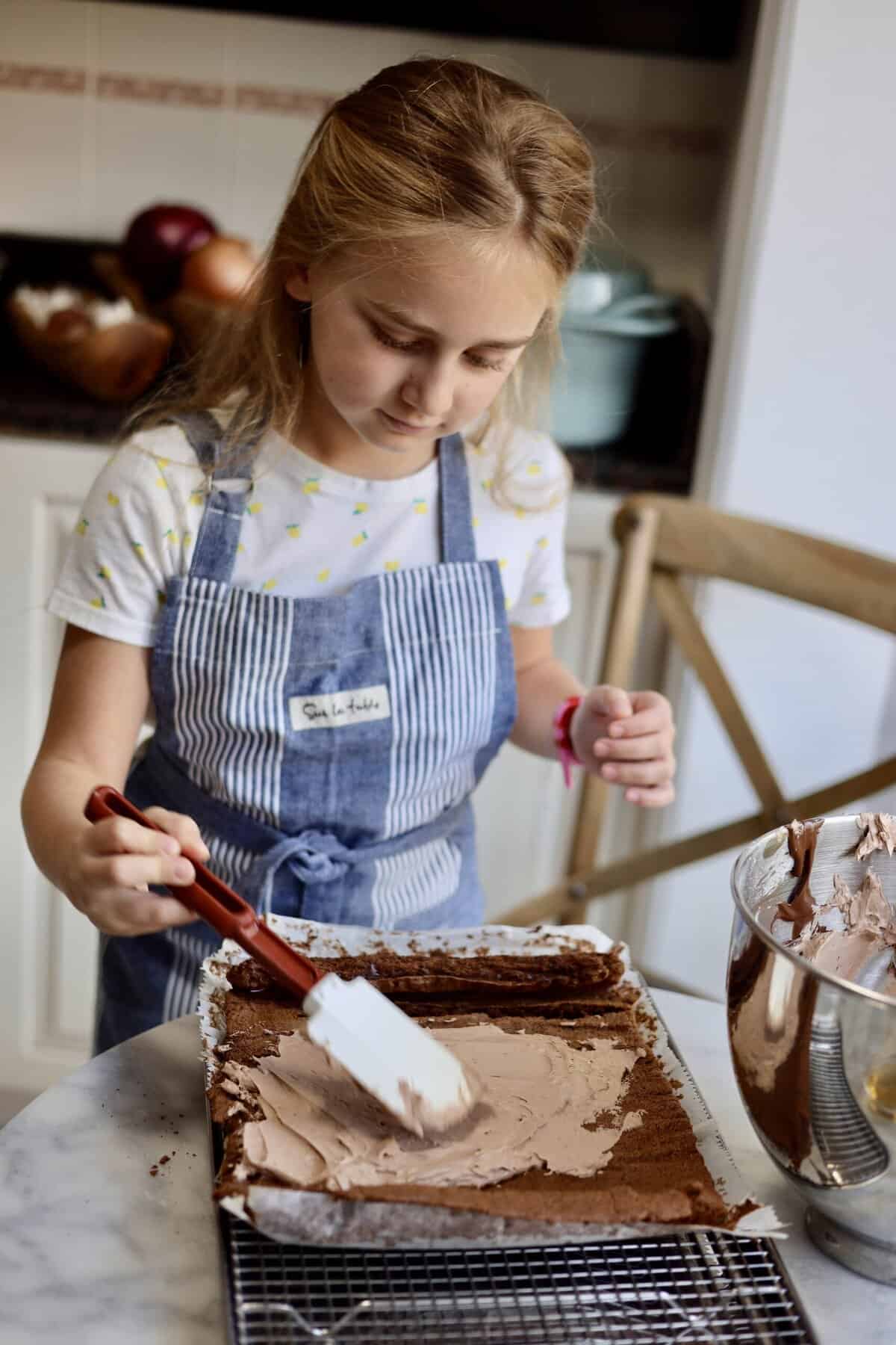 Le chefs wife daughter making a buche de noel cake - spreading the chocolate butter cream inside the chocolate chiffon cake