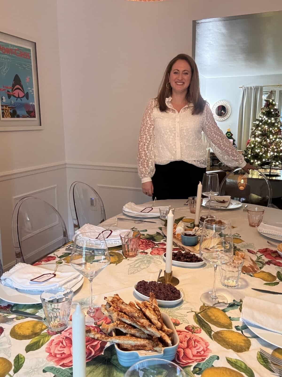 le chefs wife at her table during the holidays - a set table with holiday decor and a christmas tree in the background illustrating french hosting