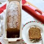close up of gingerbread spice cake in a le creuset terrine with a slice cut out on the side on a christmas plate