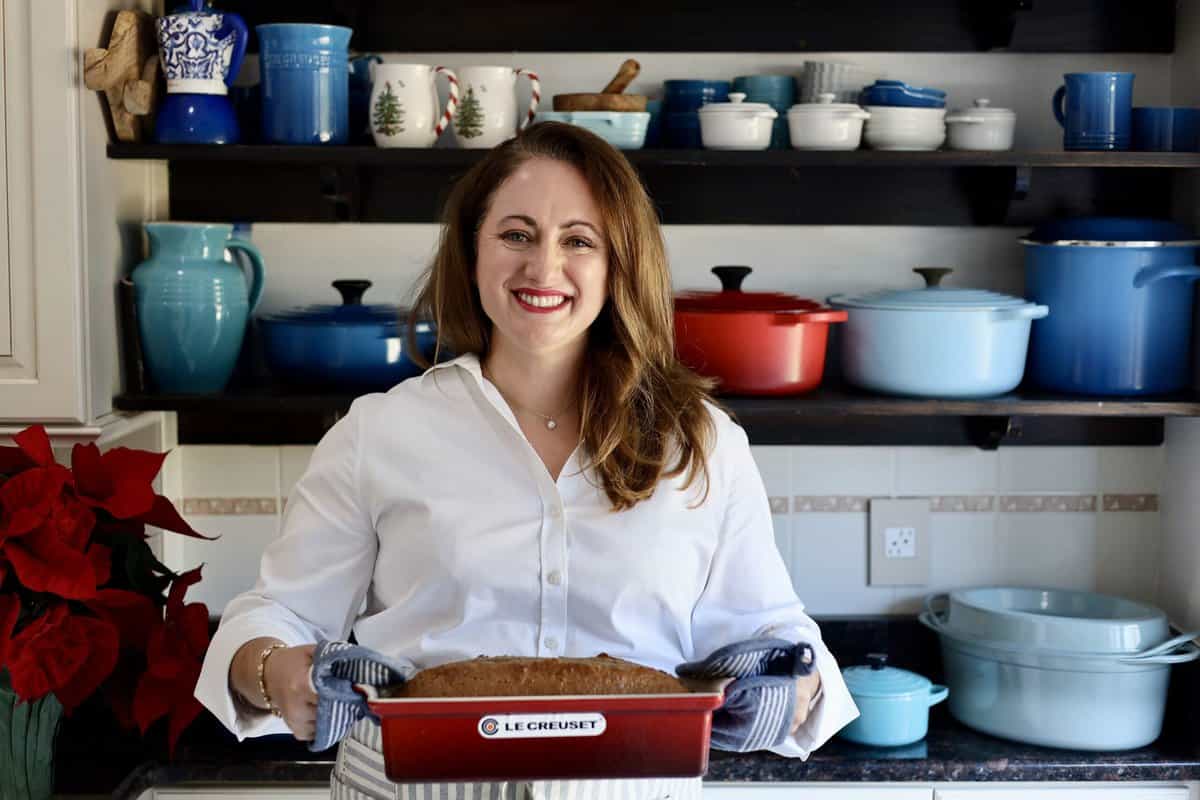 gingerbread spice cake risen in a le creuset terrine held by le chefs wife in her kitchen in front of a rack of pots