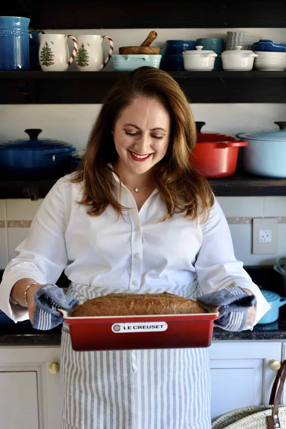 gingerbread spice cake risen in a le creuset terrine held by le chefs wife in her kitchen in front of a rack of pots