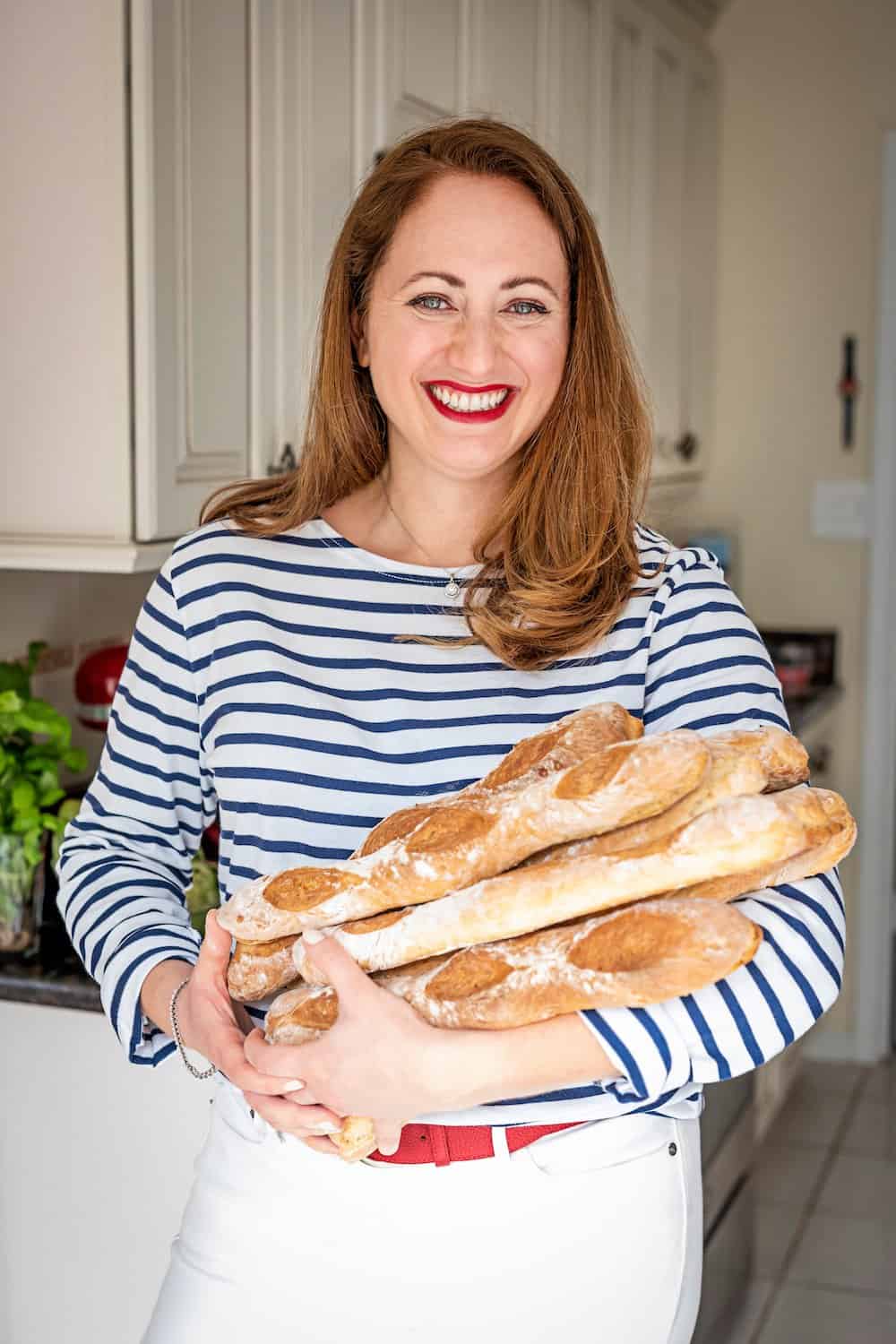 le chef's wife portrait holding a bouquet of baguettes in her kitchen