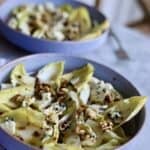 two bowls of classic endive salad with blue cheese, endives, walnuts, pears and dijon mustard