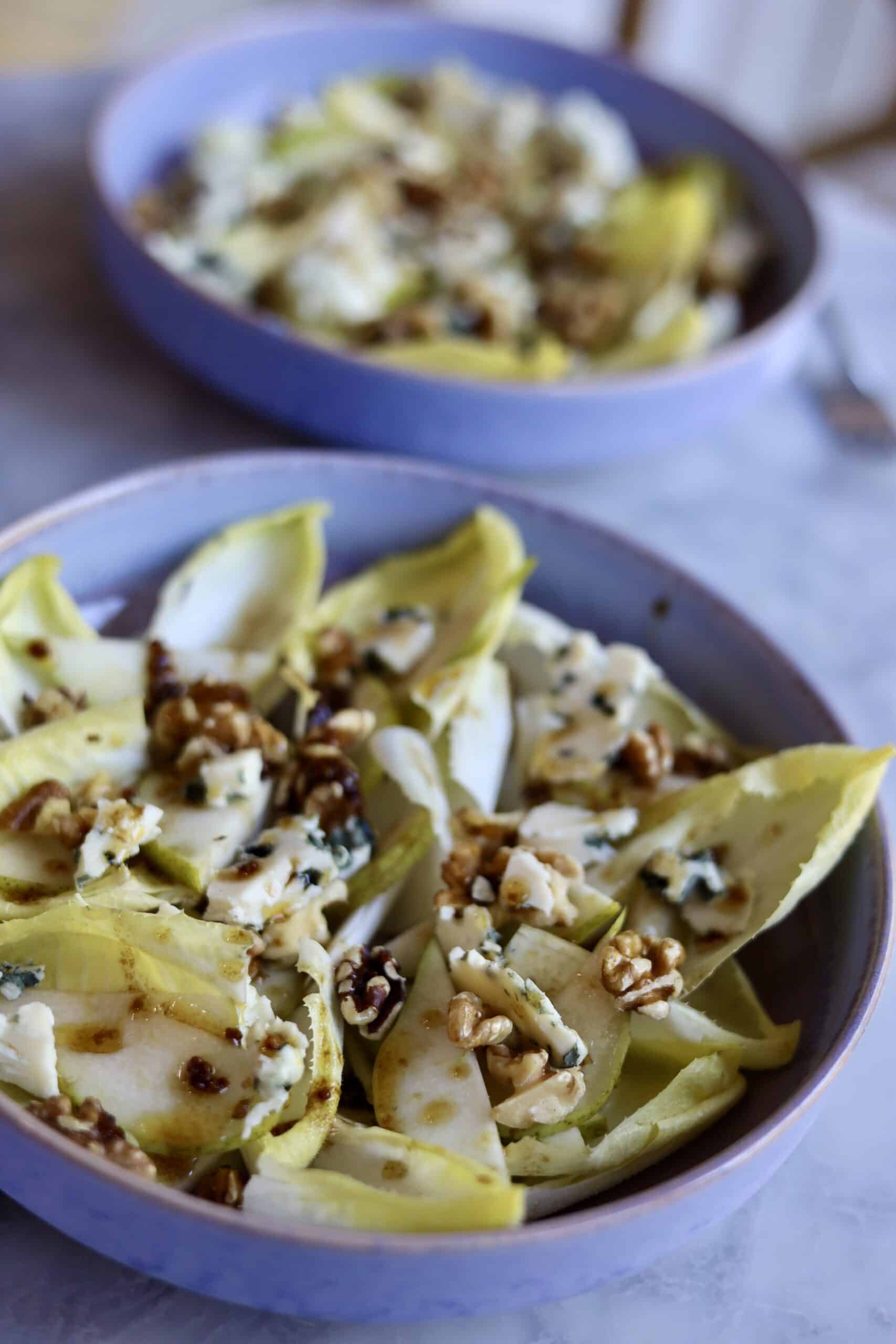 two bowls of classic endive salad with blue cheese, endives, walnuts, pears and dijon mustard