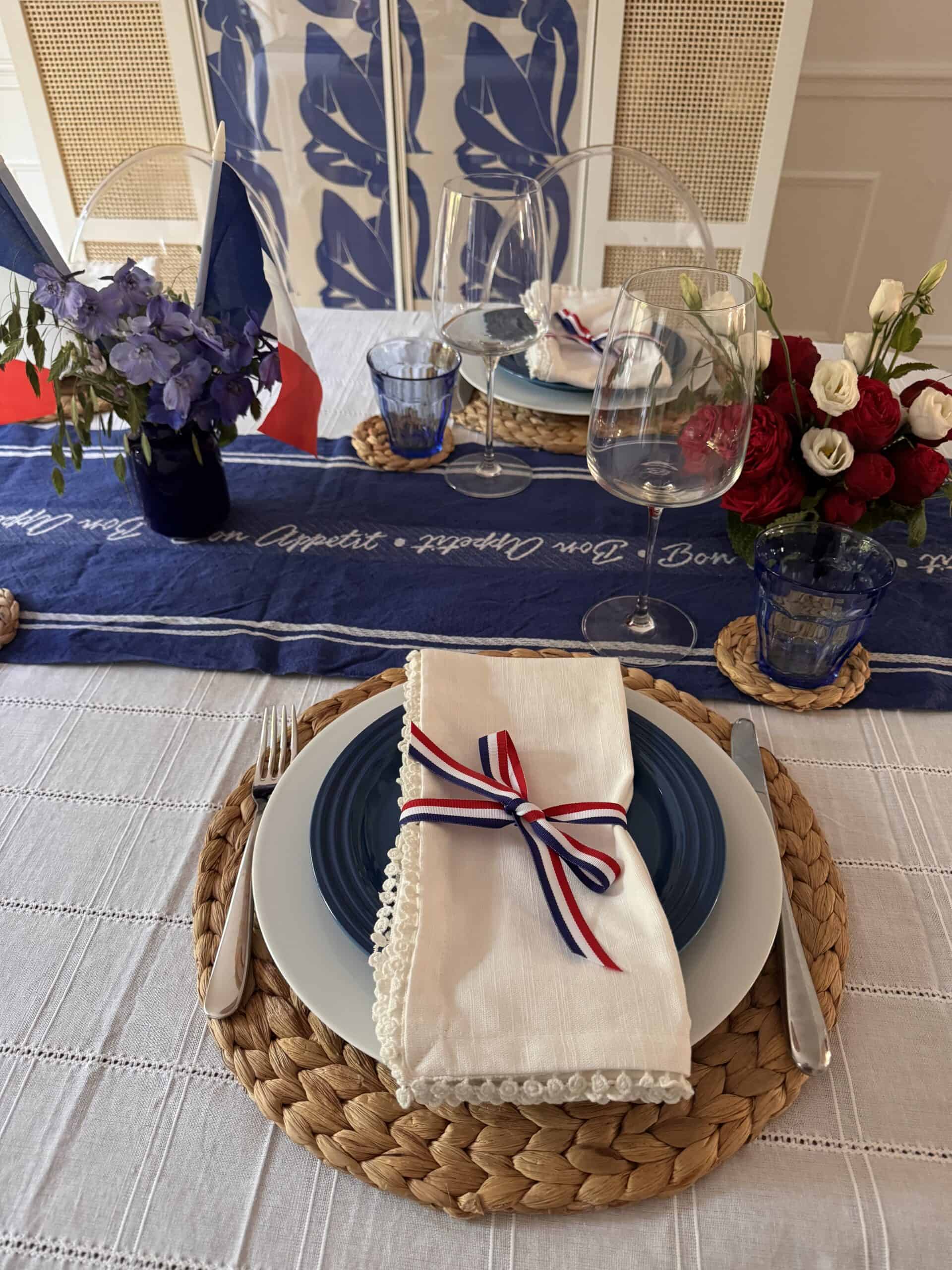 le chef's wife table set for a French themed dinner party - a white charger under a blue plate with a red white and blue ribbon