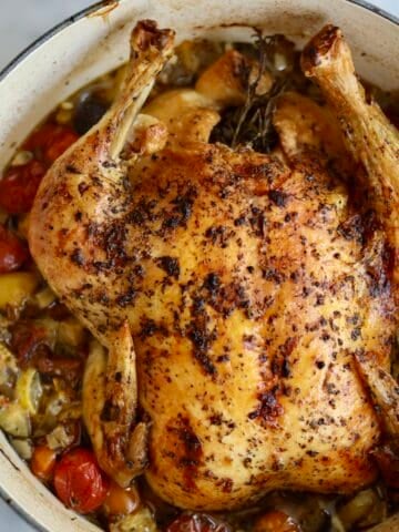 Provencal roast chicken ratatouille in a dutch oven - the chooped vegetables and herbs for the ratatouille on the bottom - fresh out of the oven- the skin is crispy