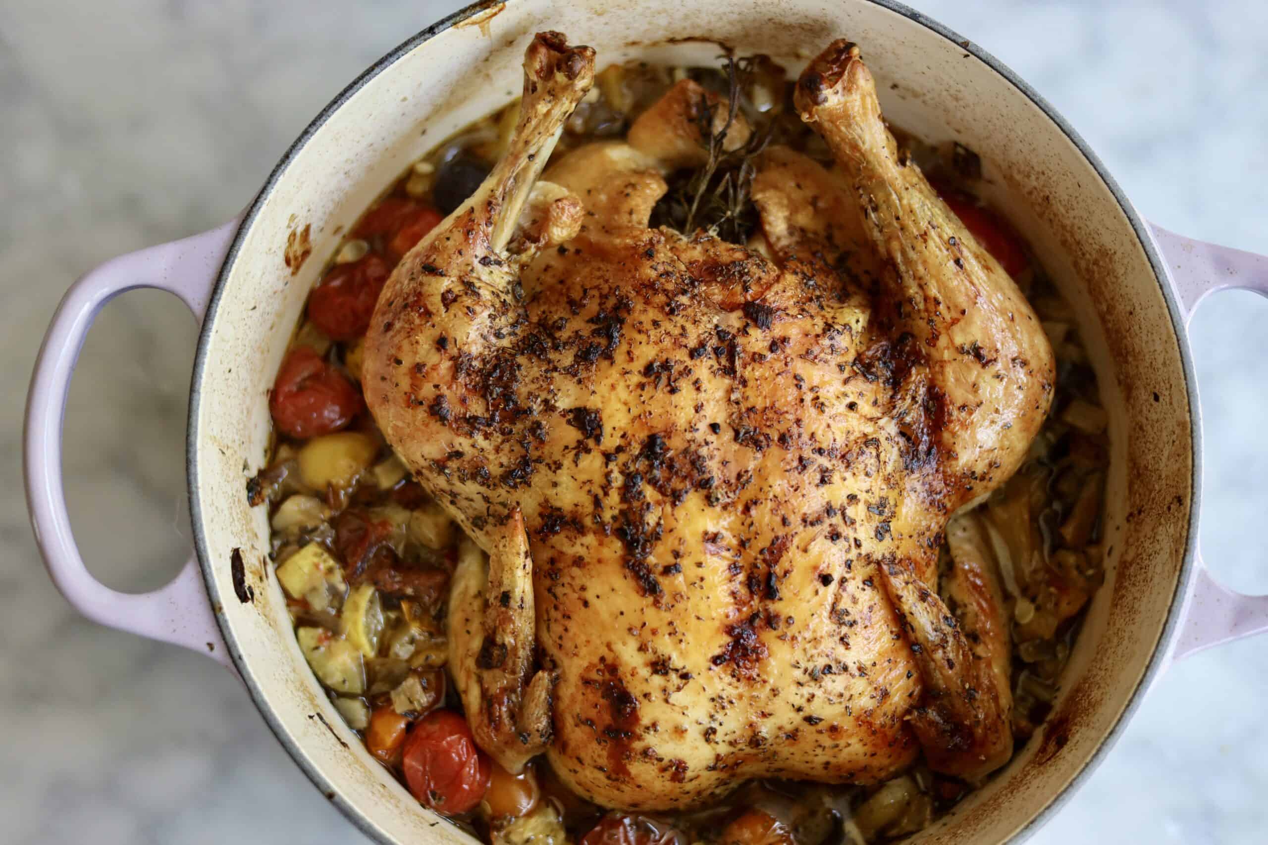 Provencal roast chicken ratatouille in a dutch oven - the chooped vegetables and herbs for the ratatouille on the bottom - fresh out of the oven- the skin is crispy