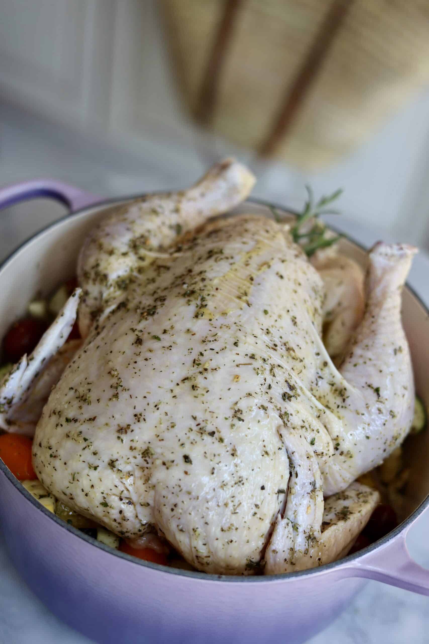 Provencal roast chicken ratatouille in a dutch oven - the chooped vegetables and herbs for the ratatouille at the bottom of the dutch oven - the chicken placed on top